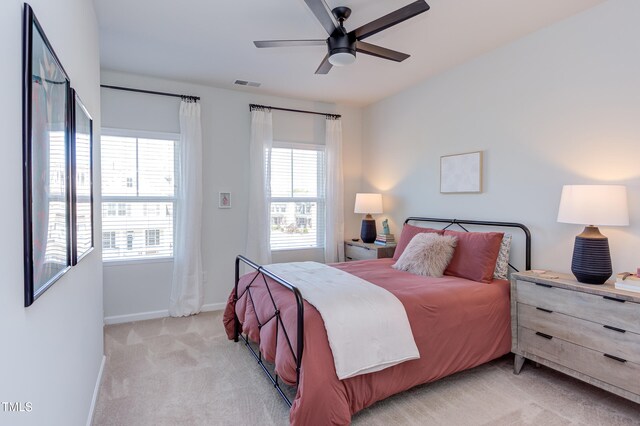 bedroom featuring a ceiling fan, light colored carpet, visible vents, and baseboards