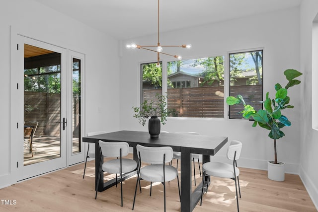 dining area with light wood-style flooring, a chandelier, and baseboards