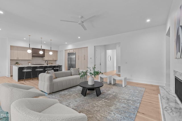 living area featuring recessed lighting, light wood-style floors, a high end fireplace, a ceiling fan, and baseboards