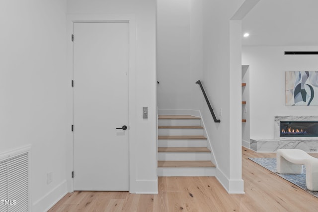 stairs featuring built in shelves, a fireplace, visible vents, wood finished floors, and baseboards