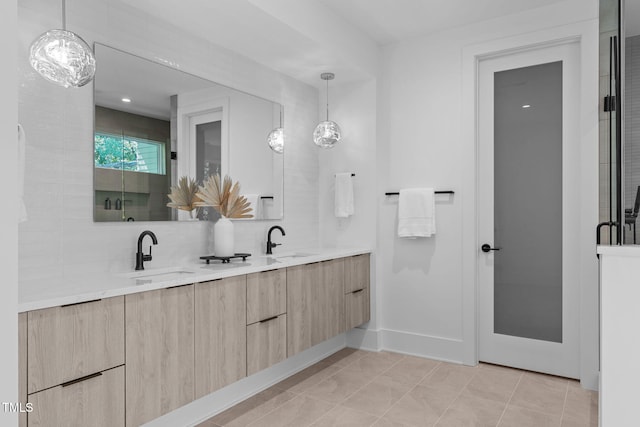 bathroom featuring tile patterned floors, a sink, backsplash, and double vanity