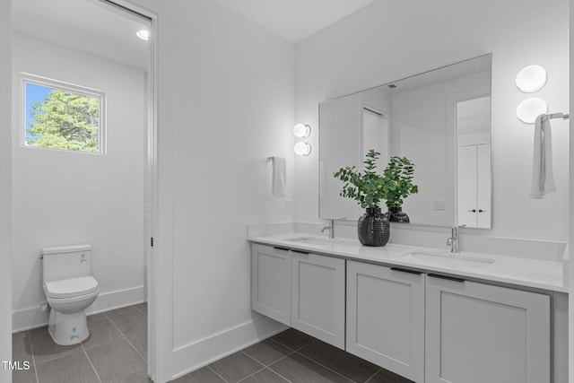 full bath with tile patterned flooring, a sink, baseboards, and double vanity