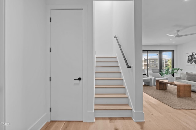 stairway with ceiling fan and wood finished floors