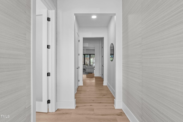 corridor with light wood-style floors and baseboards