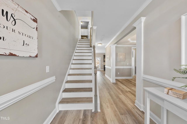 stairs featuring ornamental molding, decorative columns, baseboards, and wood finished floors