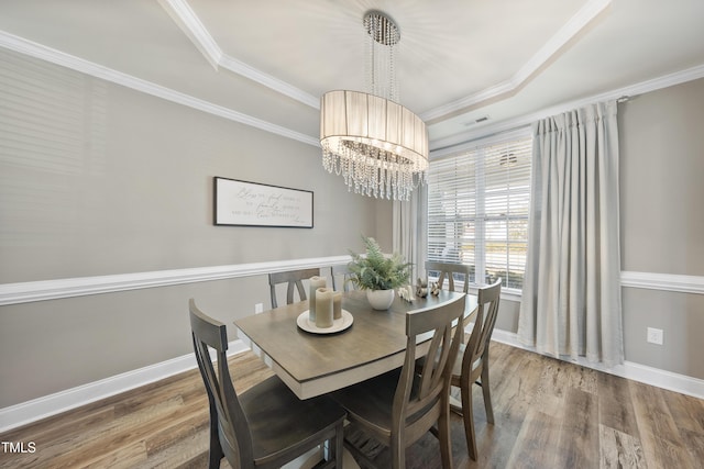 dining room featuring baseboards, a tray ceiling, wood finished floors, and crown molding