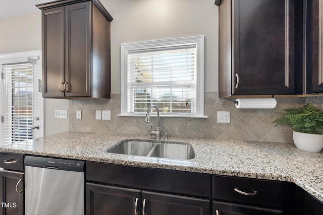 kitchen with decorative backsplash, dark brown cabinetry, a sink, light stone countertops, and dishwasher