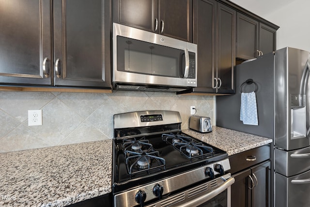 kitchen featuring light stone countertops, tasteful backsplash, appliances with stainless steel finishes, and dark brown cabinets