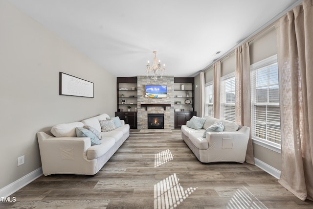 living area with baseboards, wood finished floors, and a stone fireplace