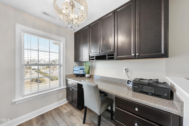 office area featuring light wood-style flooring, visible vents, baseboards, built in study area, and an inviting chandelier