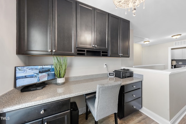 kitchen featuring dark brown cabinetry, visible vents, light countertops, light wood-type flooring, and built in study area