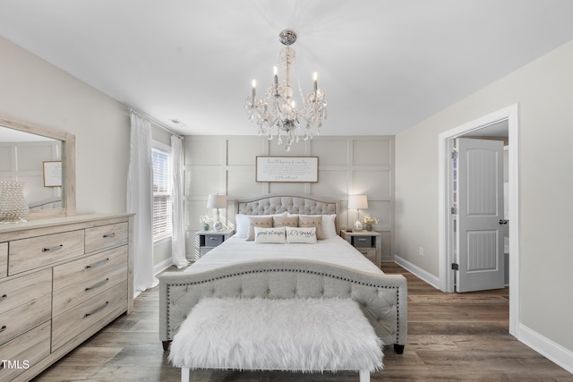 bedroom featuring a notable chandelier, baseboards, and wood finished floors