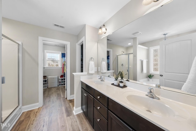 bathroom featuring visible vents, a sink, a shower stall, and wood finished floors