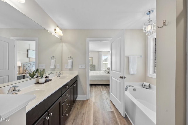 bathroom featuring double vanity, a sink, wood finished floors, and ensuite bathroom