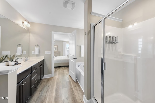 ensuite bathroom with visible vents, a stall shower, connected bathroom, vanity, and wood finished floors