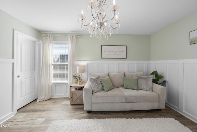 living room featuring a chandelier, wainscoting, wood finished floors, and a decorative wall