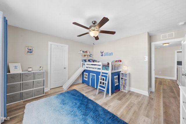 bedroom featuring a ceiling fan, wood finished floors, visible vents, and baseboards