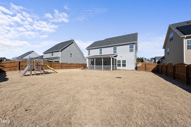 rear view of property with a playground, a fenced backyard, and a sunroom