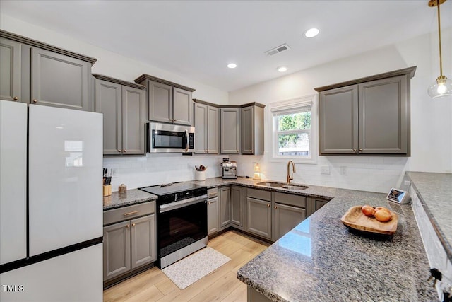 kitchen with range with electric cooktop, visible vents, stainless steel microwave, decorative light fixtures, and freestanding refrigerator