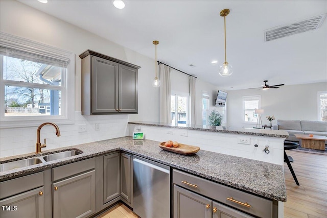 kitchen featuring a peninsula, a sink, visible vents, and pendant lighting