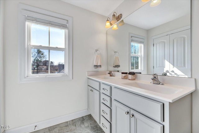 full bath with a closet, a sink, baseboards, and double vanity