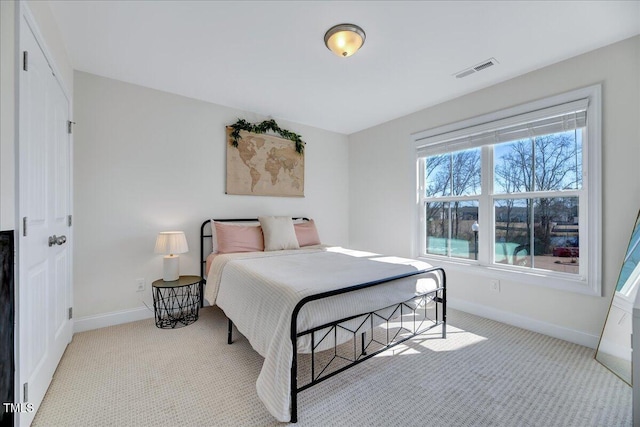 bedroom with baseboards, visible vents, and light colored carpet