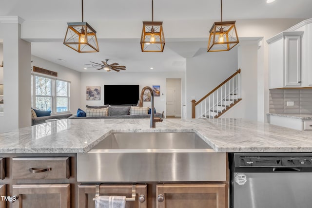 kitchen featuring decorative backsplash, stainless steel dishwasher, open floor plan, a sink, and ceiling fan