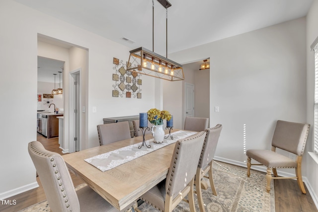 dining room featuring wood finished floors, visible vents, and baseboards