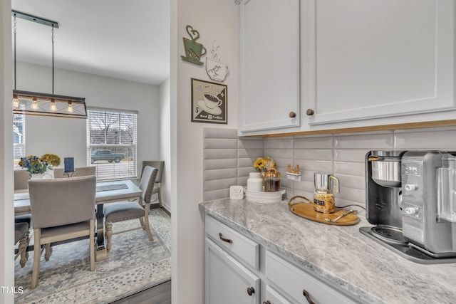 kitchen with white cabinetry, decorative backsplash, and decorative light fixtures