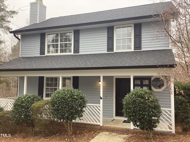 view of front of house featuring roof with shingles and a chimney