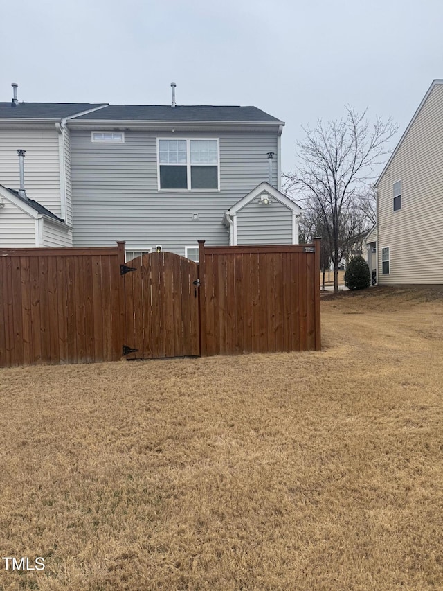 rear view of property featuring a yard and fence