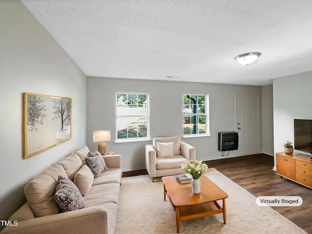 living room featuring dark wood-style floors, a textured ceiling, baseboards, and heating unit