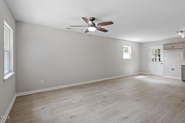 spare room with visible vents, a ceiling fan, light wood-style flooring, and baseboards