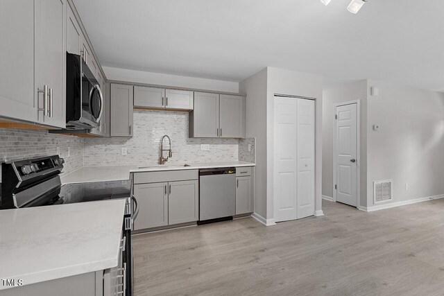 kitchen featuring visible vents, stainless steel appliances, light countertops, gray cabinetry, and a sink