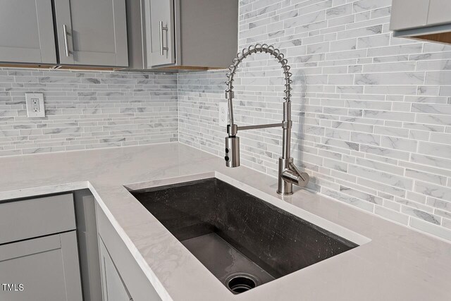 kitchen with gray cabinets, light countertops, a sink, and decorative backsplash