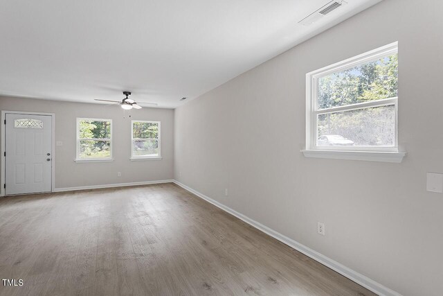 empty room featuring visible vents, ceiling fan, light wood-style flooring, and baseboards