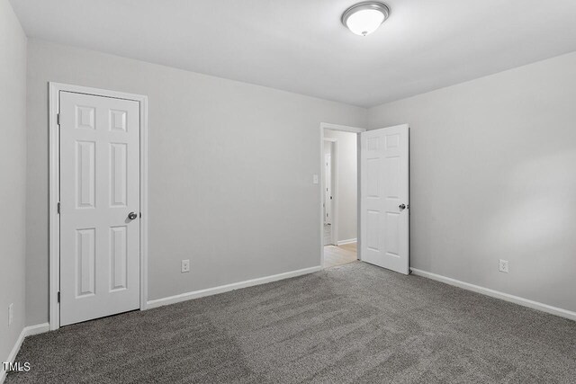 carpeted empty room featuring baseboards