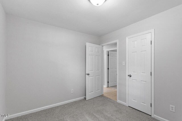 unfurnished bedroom featuring baseboards and light colored carpet