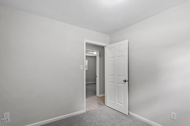 unfurnished bedroom featuring light carpet and baseboards