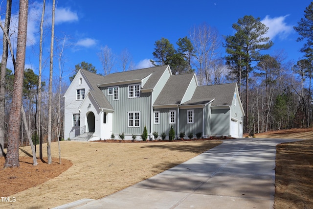 view of front of property featuring board and batten siding, driveway, a shingled roof, and a garage