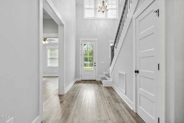 entrance foyer with stairs, light wood-style flooring, visible vents, and a notable chandelier