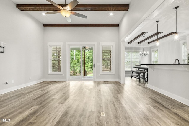 unfurnished living room featuring beam ceiling, baseboards, and wood finished floors