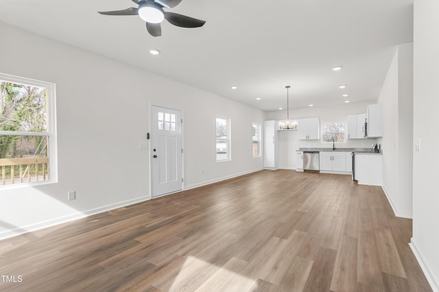 unfurnished living room with light wood finished floors, baseboards, a sink, and recessed lighting