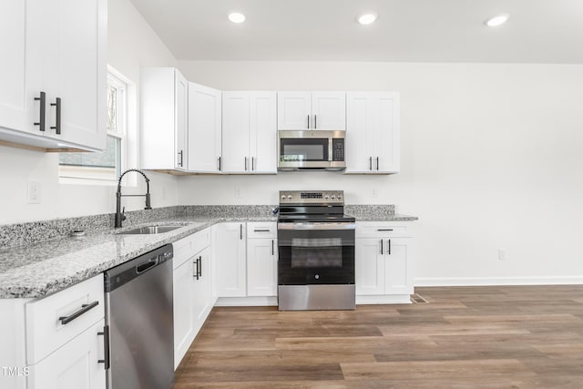 kitchen with light wood-style flooring, appliances with stainless steel finishes, light stone counters, white cabinetry, and a sink