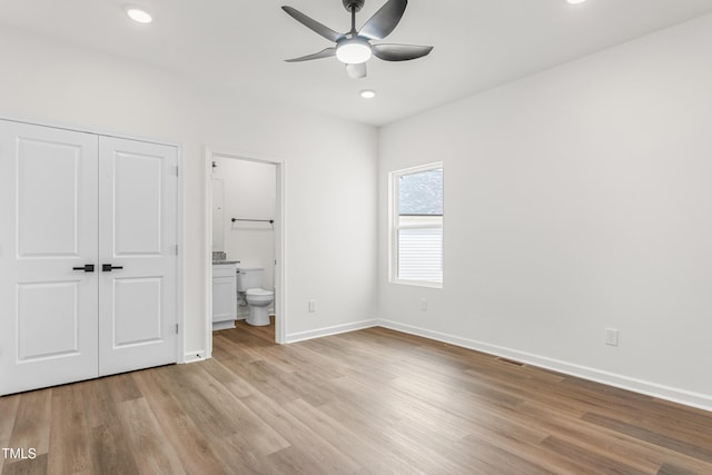 unfurnished bedroom with a closet, ensuite bath, light wood-style flooring, and baseboards