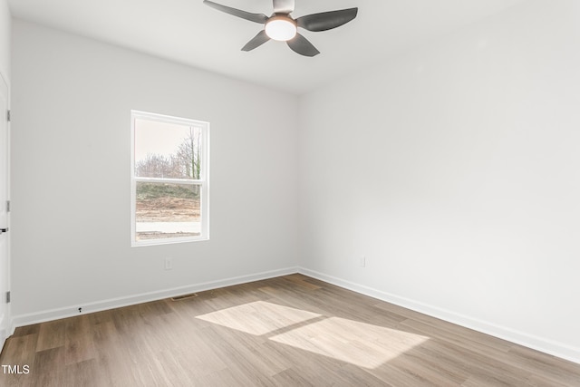 empty room featuring ceiling fan, light wood-style flooring, and baseboards