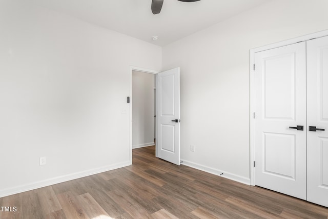 unfurnished bedroom with a closet, ceiling fan, baseboards, and wood finished floors