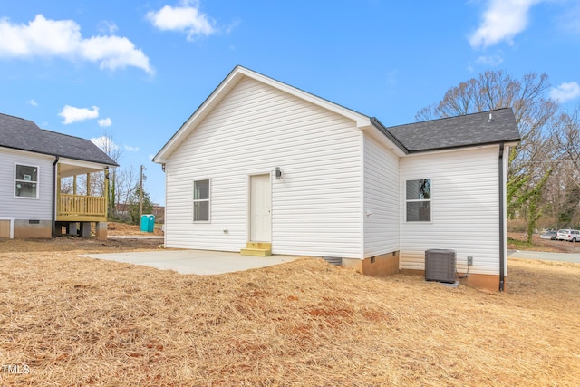 rear view of property featuring a patio, central air condition unit, a shingled roof, crawl space, and a lawn