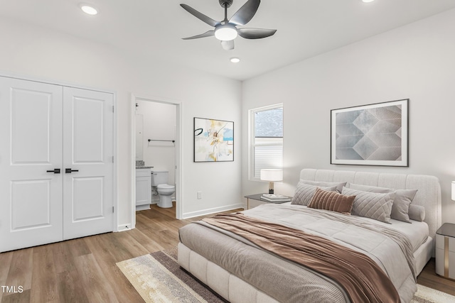 bedroom featuring ensuite bathroom, light wood-style flooring, recessed lighting, baseboards, and a closet