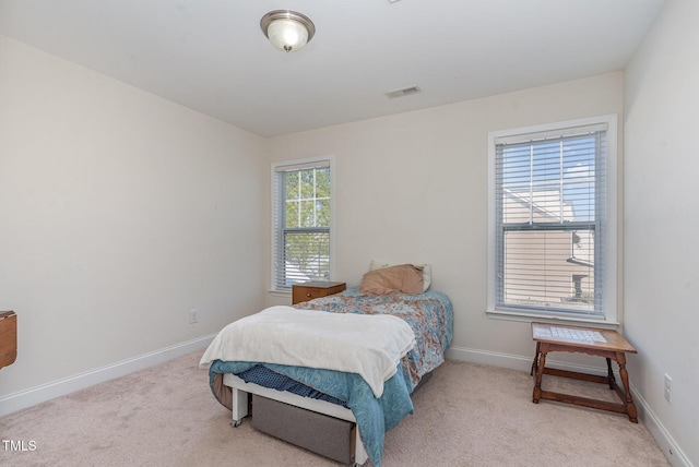 bedroom with baseboards, visible vents, and light colored carpet